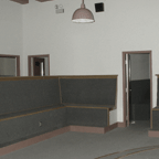 Empty room with built-in corner seating and open door.
