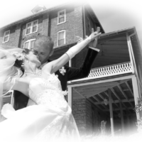 Bride and groom kissing outside large building.