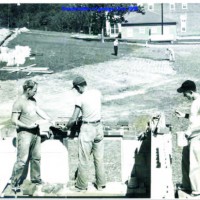 Three men working on construction in an outdoor setting.